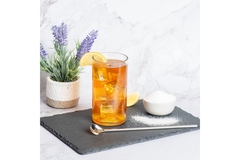 Image A tall glass of iced tea with a small bowl of a powdered sweetener next to it.
