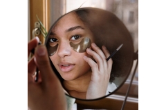 Image Woman looking into mirror wearing under eye mask