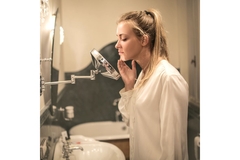 woman in bathroom looking at skin in mirror