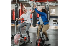 Image Overweight person and fit person on treadmills giving each other a high five.