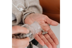 Person taking a supplement capsule out of a bottle.