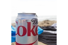 Image Can of diet Coke on a beach.
