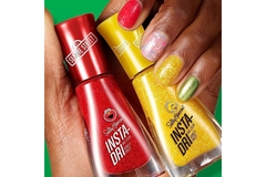 Image A woman with painted nails holds two nail polish bottles from the Sesame Street collection of the brand Sally Hansen.