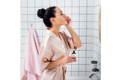 Image A woman applies a retinol serum while looking into the mirror.