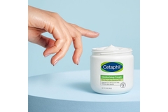 Image A hand reaches for a jar of Cetaphil skin cream.