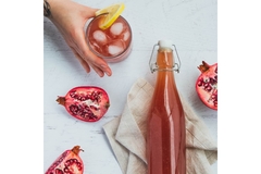 Image Glass bottle of fermented tea and hand reaching to serve in a glass
