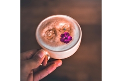 Image A person's hand holding a cup of violet coffee.