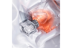 Image A fragrance bottle lays on top of silk fabric.