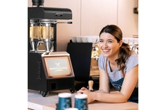 Woman resting hands on a table with a coffee machine.