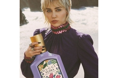 Image Miley Cyrus models with an oversized bottle of perfume.