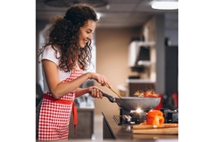 Image Woman cooking at home with pan in hand.