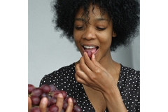 Woman eating a grape.