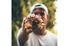 Image Man holding a half eaten burger