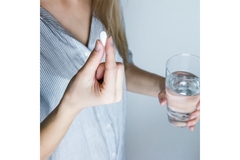 Person taking a capsule with a glass of water