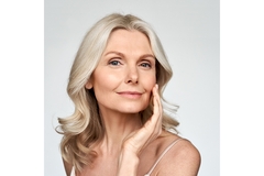 A smiling woman with silver hair and smooth skin.