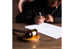 Judge sitting behind desk, writing a paper.