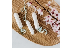 Tampons lie on a wooden surface surrounded by cherry blossom flowers.