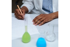 Image Colored Liquids on Flasks while researcher takes notes