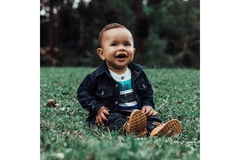 Image Laughing baby sitting in the grass.