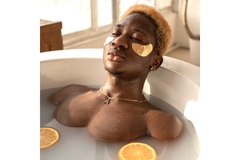 Image man relaxing in a bath with milky water with orange peels and under eye strips