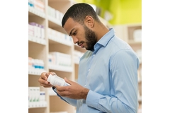 Man looking at the label of a supplement jar.
