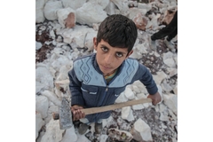 Image boy holding a large hammer standing on large rocks
