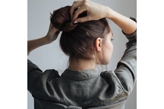 Woman's back to camera tying her hair in a bun.
