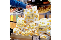 Image A hand grabbing a bag of product in a grocery store.