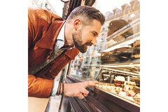 Man looking through window at bakery in Paris.