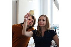 A male and a female scientist in lab looking at a petridish.
