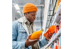 Image Man in supermarket looking at labels of two products.