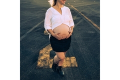 Image A pregnant woman walks on the street holding her tummy and smiling.