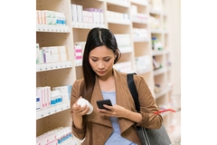 Woman shopping a supplement in a pharmacy, checking out the label.