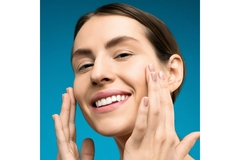 Image Woman touches cheeks while smiling