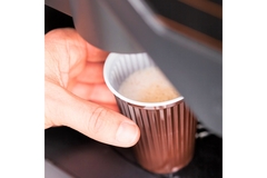 Image Automatic coffee vending machine with a hand holding a glass of coffee.