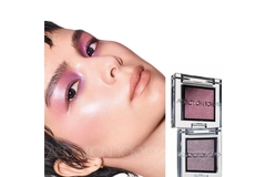 Image Woman's face with clean makeup lying horizontally next to two eye shadow pallets.