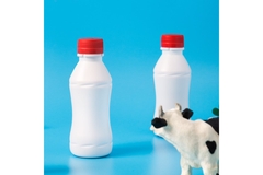 Image Two white milk bottles in front of a blue background.