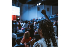 Image Woman raising her hand in a fist at a conference.