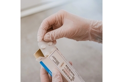 Image person pulling out medicine from a white and blue paper pack