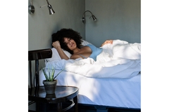 Image A woman sleeps on her bed and looks well-rested.
