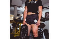 Image A woman holds a large weight at the gym.