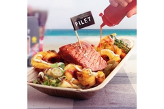 Image Revo Foods' salmon fillet plated with red sauce being poured over it.