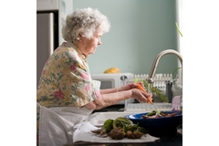 Image An elderly woman washes vegetables in the kitchen sink.
