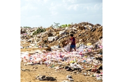 A boy walking around in a landfill.