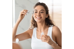 A woman applying face serum.