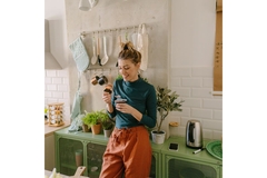 Image Woman in a kitchen eating a healthy snack.