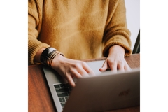 A woman's hands on a computer typing.