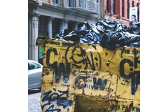 A dumpster filled with garbage bags.