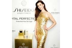 Image Anne Hathaway poses on a red carpet next to Shiseido's Vital Perfection skin care products.
