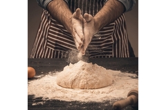 Image A man's hand dusting off flour on a table.